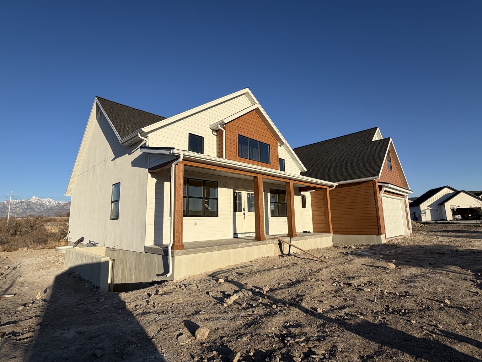 New-build home with white board-and-batten siding and cedar-tone gable accents