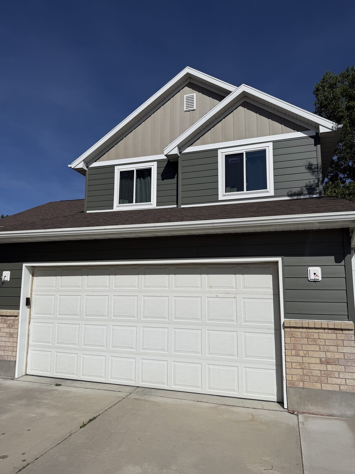 Green lap siding with board-and-batten gables above a two-car garage