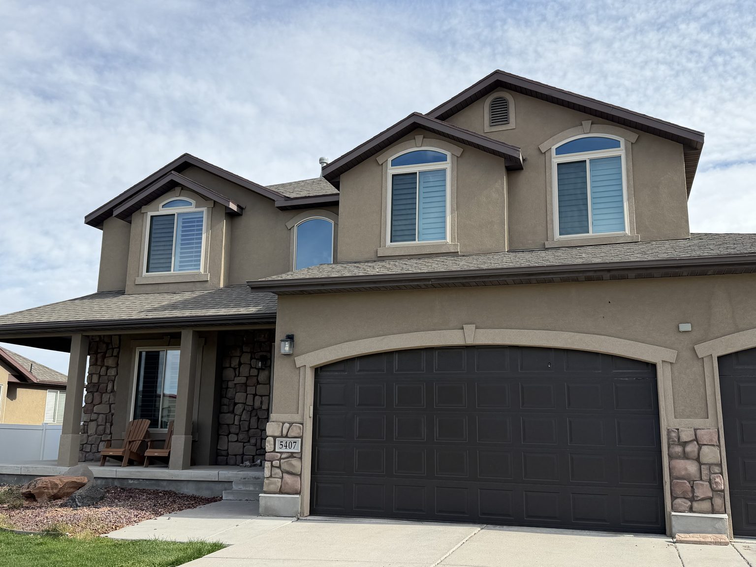 Two-storey stucco and stone home after window replacement