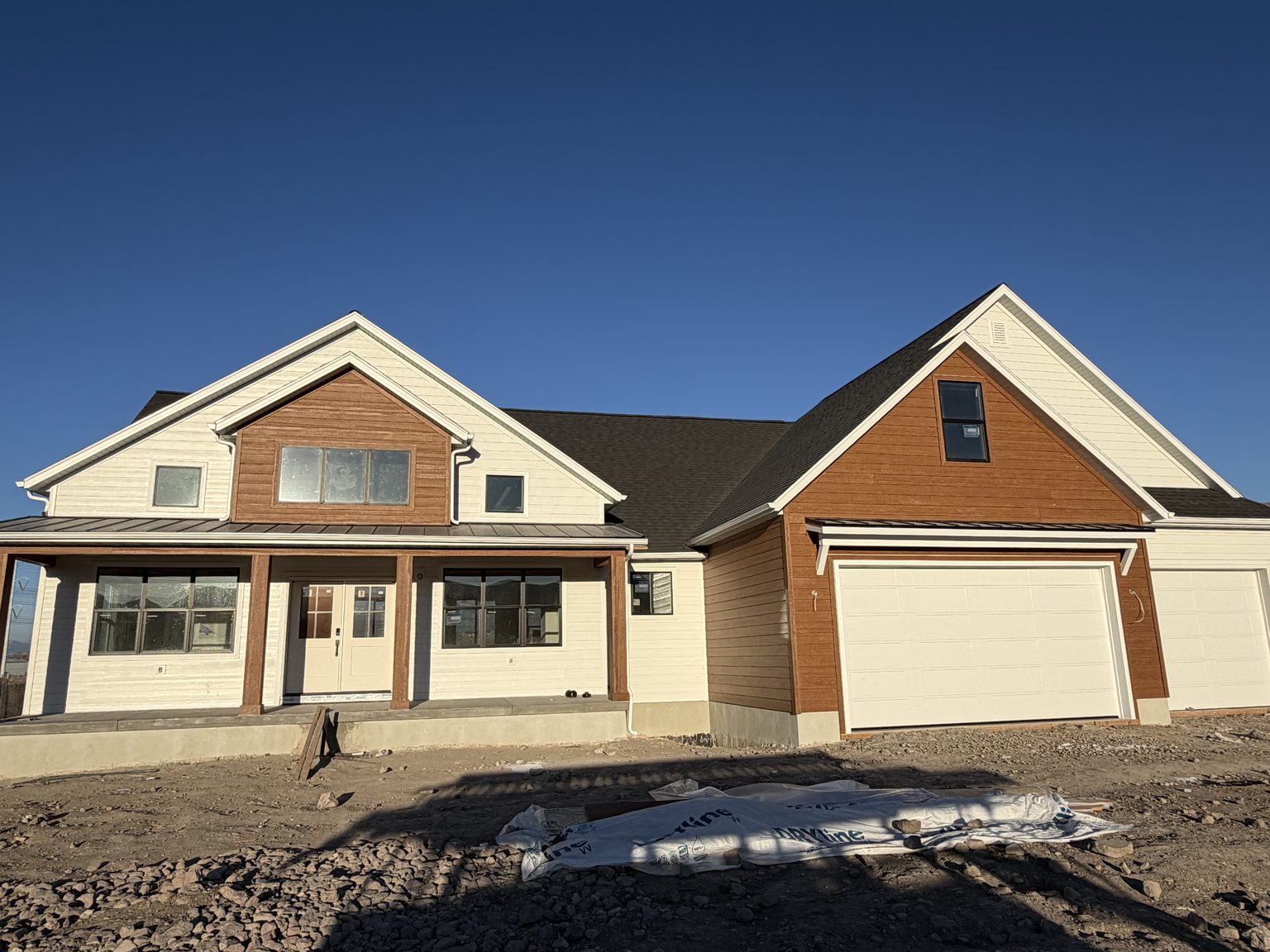 Front elevation of a new home in white lap siding with cedar-tone gables and trim